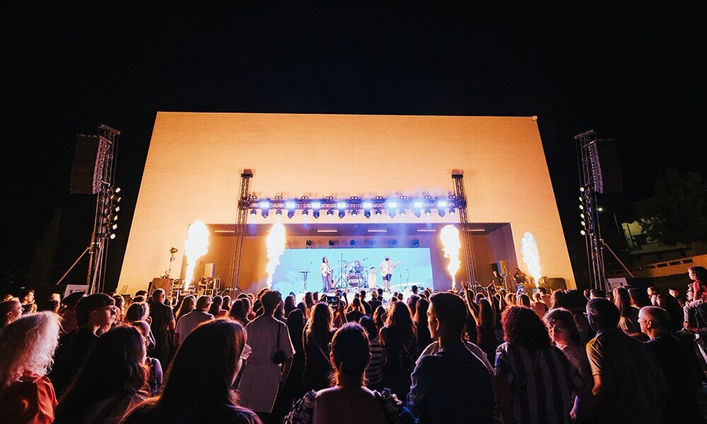 concerto em palco exterior com pessoas a ver